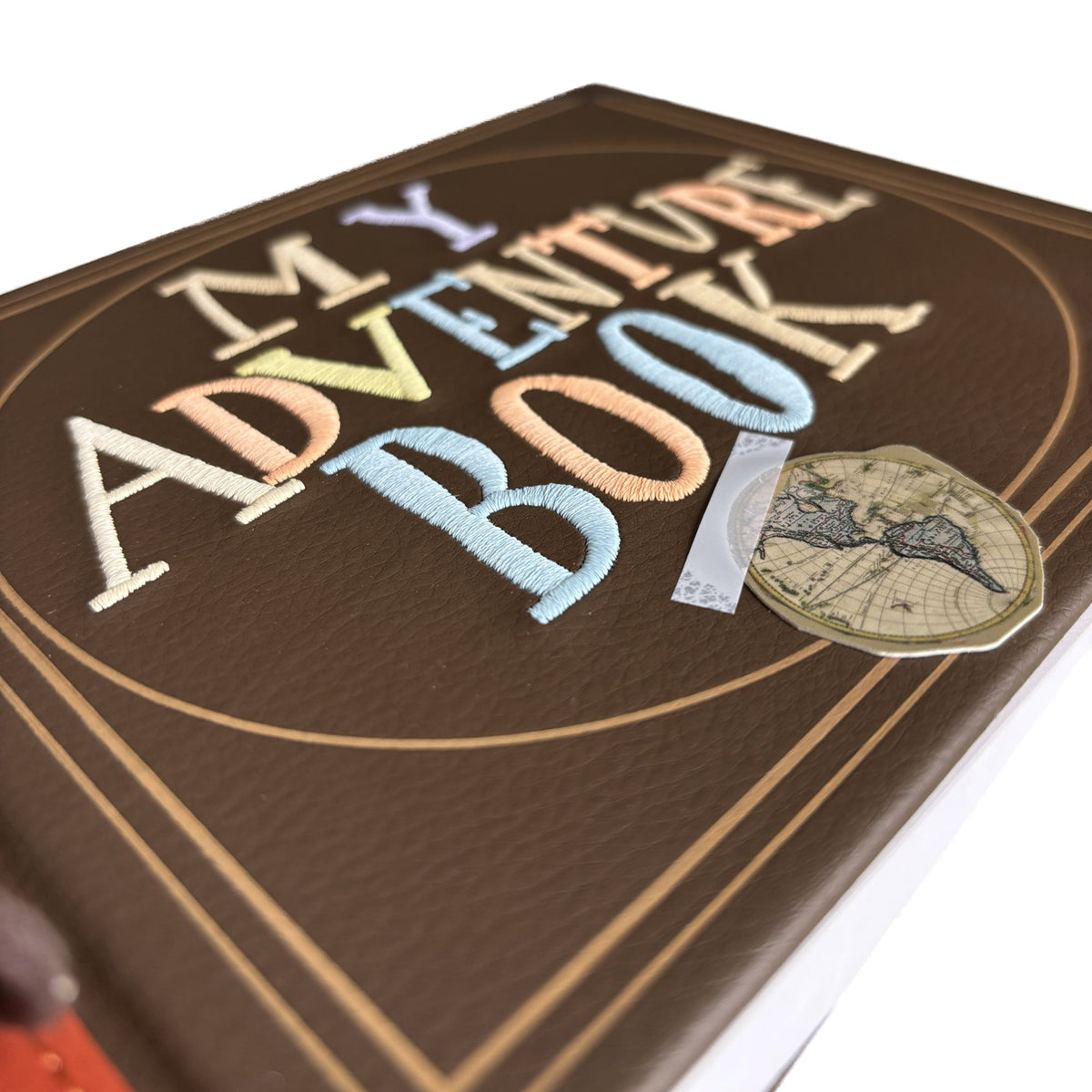 Abenteuerbuch Mini-Nachbildung aus Disney Pixar Oben, Nahaufnahme von Stickerei und Kartenmotiv auf dem Einband.